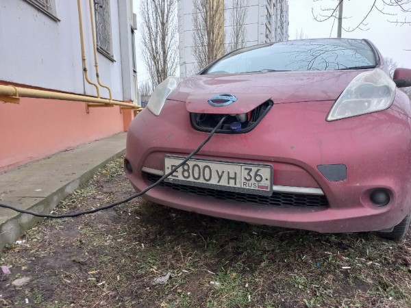 Житель Воронежа под балконом, портя газон, заряжает свой экологичный электромобиль